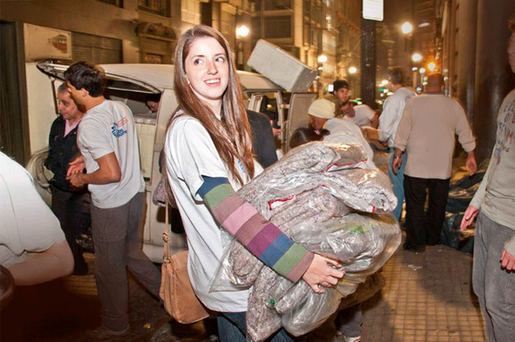 Voluntários distribuindo cobertores produzidos pela Fibran.