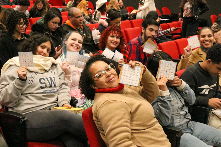 Convidados e alunos segurando cartelas de Bingo, no auditório do Centro Universitário Assunção