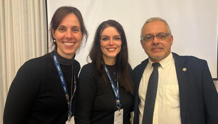 A Reitora Prof.ª Dr.ª Karen Ambra (ao centro), a Procuradora Institucional Luciana Savoy Rossi (à esquerda) e o Diretor de Regulação da SERES/MEC, Dr. Daniel Ximenes (à direita), posam sorridentes para a foto durante o seminário da ANEC, usando crachás do evento.